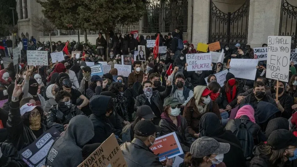 مظاهرة في إسطنبول ضد اعتقال الصحفيين، حيث يجلس محتجون يحملون لافتات تعبر عن مطالبهم السياسية.
