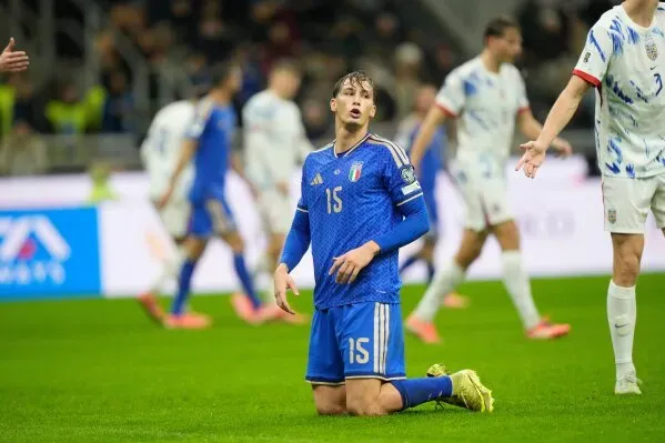 لاعب إيطالي يرتدي الزي الأزرق، جالساً على الأرض ويبدو عليه الإحباط، وسط لاعبين آخرين في مباراة تصفيات كأس العالم.