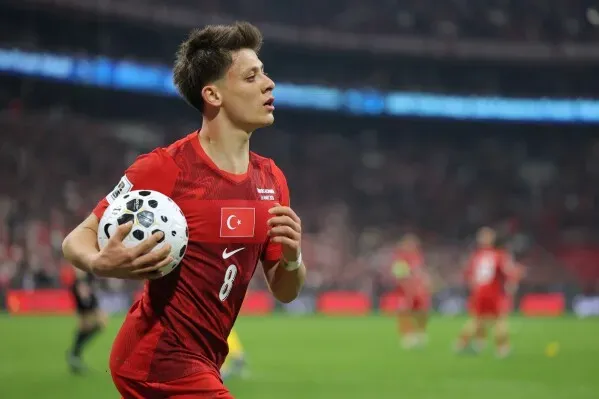 لاعب كرة قدم تركي يرتدي القميص الأحمر يحمل الكرة بعد تسجيل هدف، في مباراة حاسمة ضمن تصفيات كأس العالم.