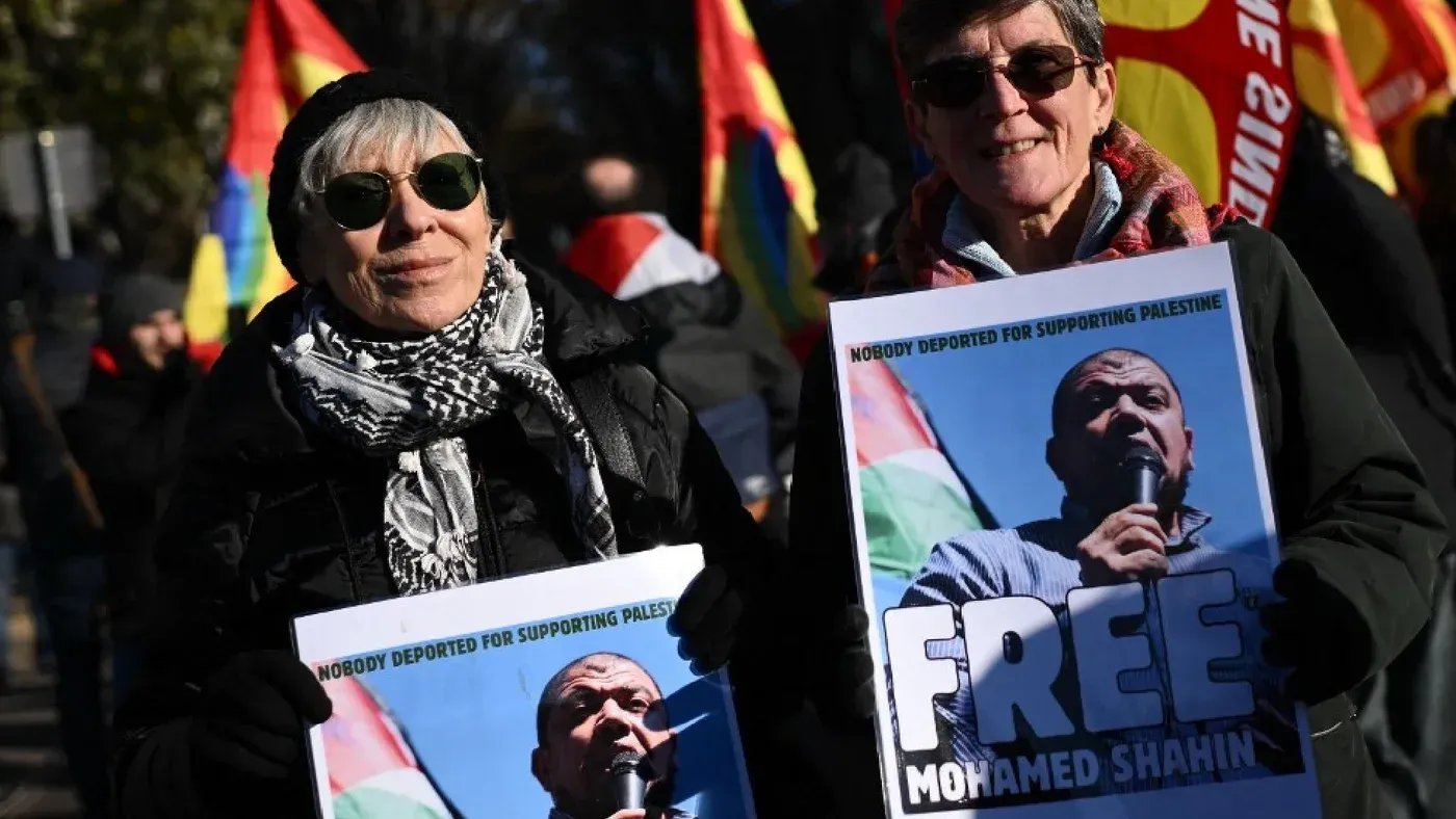 امرأتان تحملان لافتات تطالب بالإفراج عن الإمام محمد شاهين، وسط مظاهرة مؤيدة لفلسطين في إيطاليا، تعبيرًا عن التضامن.