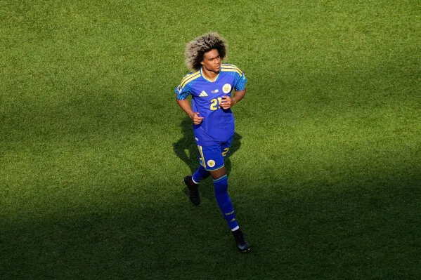 لاعب كرة قدم يرتدي زي منتخب كوراساو الأزرق، يتجه نحو الملعب وسط أجواء حماسية، في مباراة كأس العالم ضد ساحل العاج.