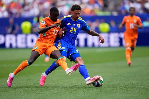 مواجهة بين لاعبين من منتخب ساحل العاج وكوراساو خلال مباراة كأس العالم، حيث يسعى اللاعب الإيفواري للسيطرة على الكرة.