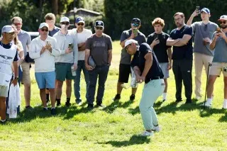 جاكوب بريدجمان يسدد الكرة في بطولة جينيسيسيس إنفيتيشنال، محاطًا بجمهور يشجعونه، مع لحظة حاسمة في مسيرته الرياضية.