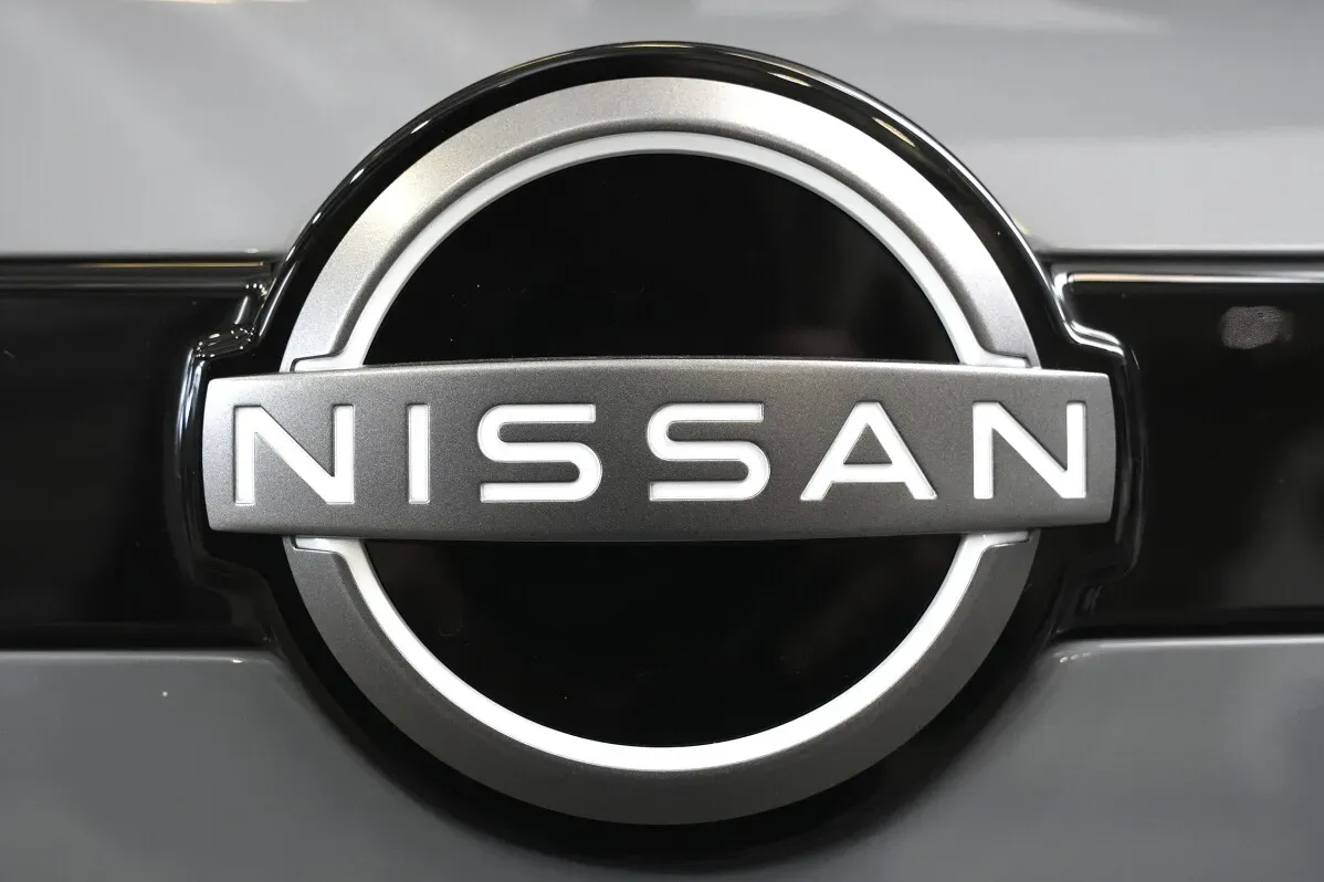 شعار شركة نيسان، يظهر في تصميم دائري مع اسم "NISSAN" باللون الفضي على خلفية سوداء، يعكس الهوية القوية لصناعة السيارات اليابانية.