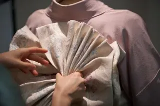 إعادة تصميم الكيمونو التقليدي، حيث تُظهر اليدان كيفية ربط وشاح "أوبي" بشكل معقد، مما يعكس فن ارتداء الكيمونو.