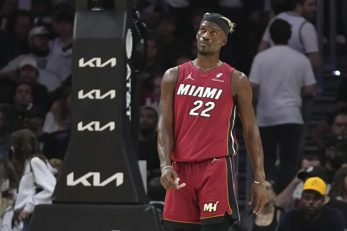 جيمي بتلر لاعب فريق ميامي هيت أثناء مباراة، يرتدي القميص الأحمر رقم 22، مع وجود جمهور خلفه في الملعب.