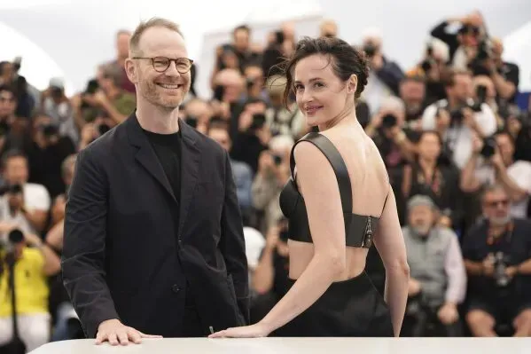 مخرج فيلم "القيمة العاطفية" يواكيم ترير والممثلة إيل فانينغ يبتسمان أمام حشد من الصحفيين في مهرجان كان السينمائي.