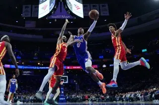 لاعب من فريق سيكسرز يسجل نقطة خلال مباراة ضد هوكس، مع وجود لاعبين من الفريق المنافس في محاولة للتصدي.