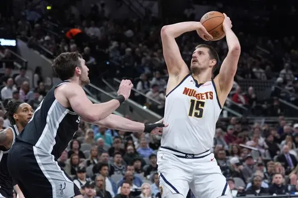 نيكولا جوكيتش يرفع الكرة للتسديد خلال مباراة دنفر ناجتس ضد سان أنطونيو سبيرز، مع تواجد لاعب سبيرز في الخلفية.