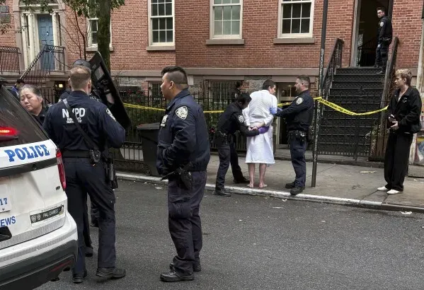 مشهد من موقع الحادث في مانهاتن، حيث يعتقل رجال الشرطة رجلًا يرتدي رداءً أبيض، بينما يتجمع الضباط حوله.