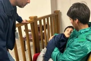 صبي صغير في حضن والده في مركز احتجاز، يعكس معاناتهم وسط ظروف قاسية، مما يسلط الضوء على قضايا الهجرة في الولايات المتحدة.