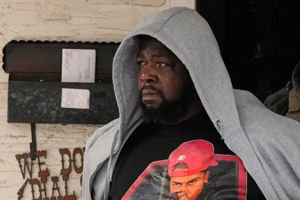 رجل يرتدي سترة بغطاء رأس، يبدو عليه القلق، يقف أمام مدخل متجر في مينيابوليس، وسط توترات حول قوانين الهجرة.