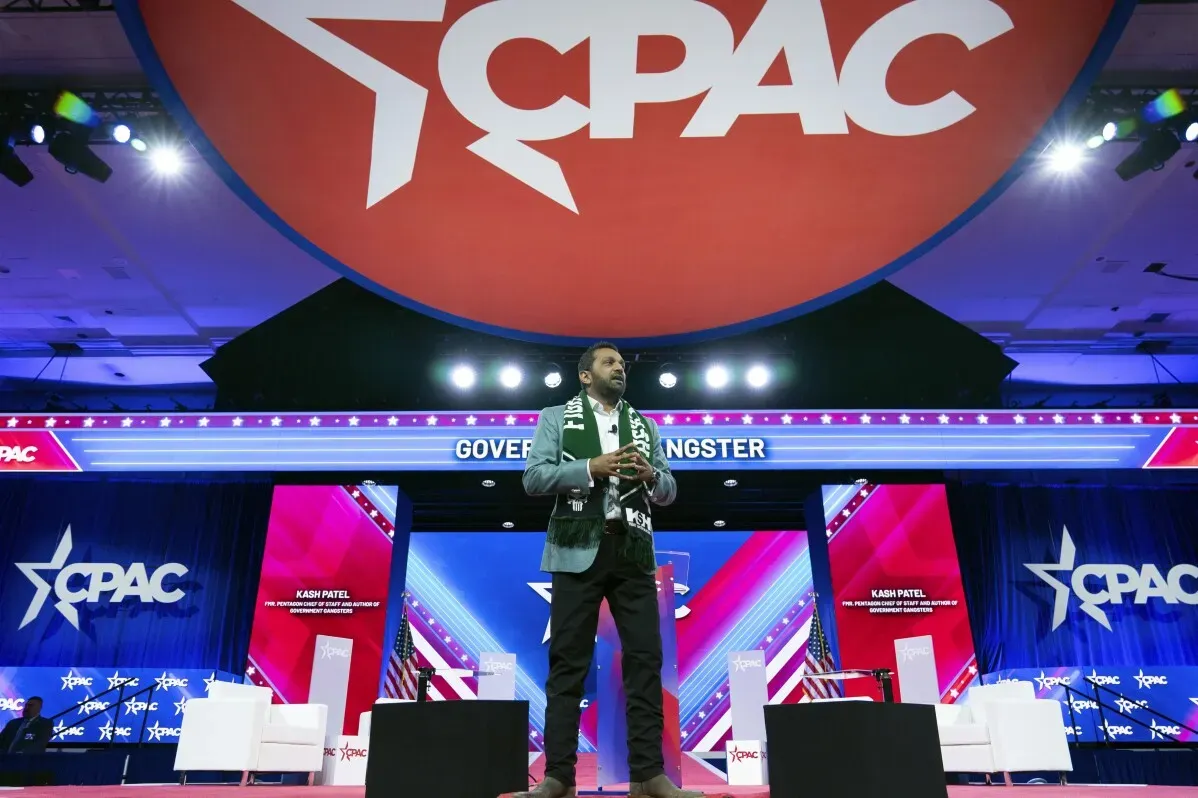 كاش باتيل يتحدث على المنصة خلال مؤتمر CPAC، مع شعار المؤتمر بارز خلفه، حيث يستعرض آرائحه حول القضايا السياسية.