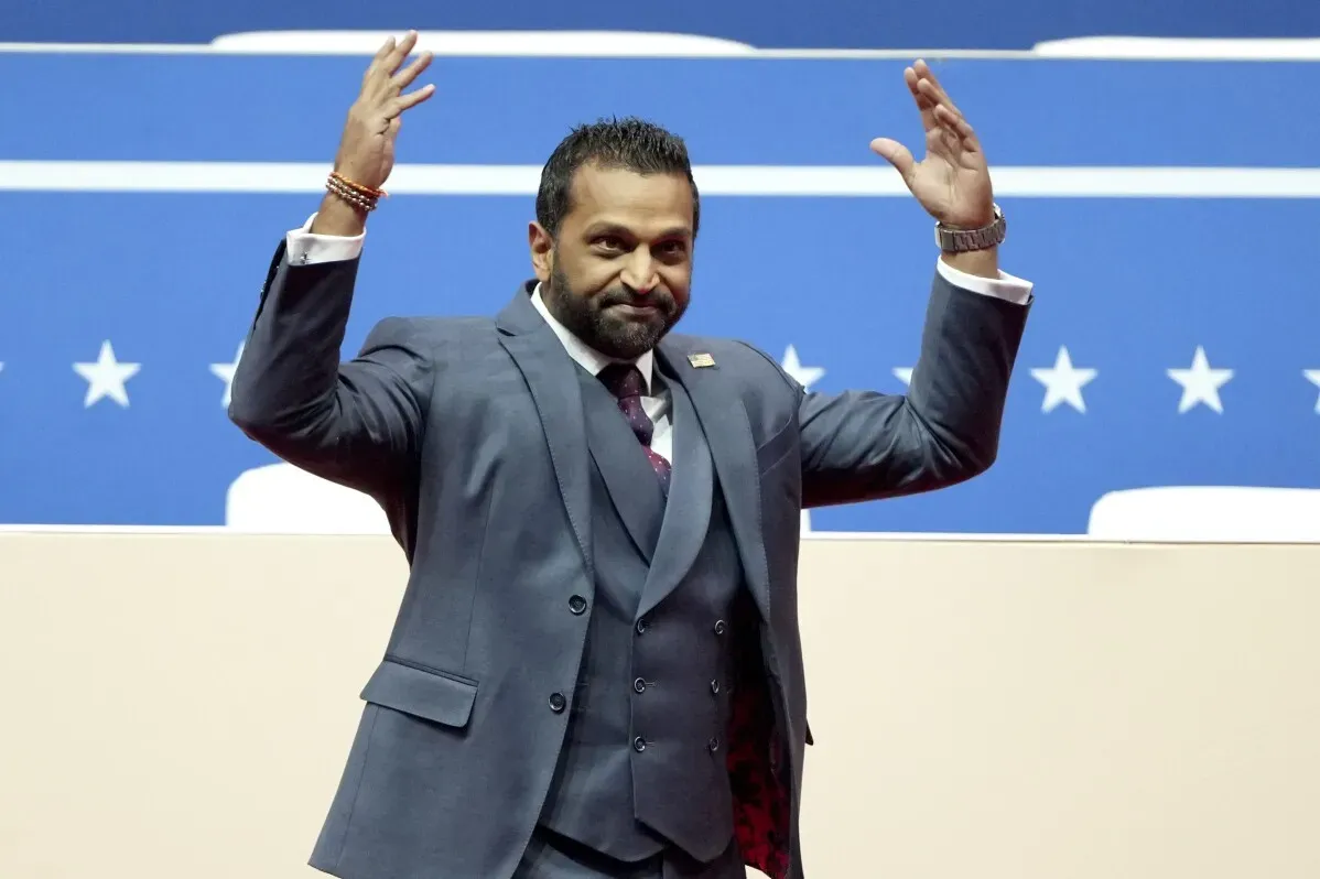 كاش باتيل، مستشار ترامب السابق، في مؤتمر يظهر حماسًا واضحًا، محاطًا بعلم يضم نجومًا. تعكس تعابيره دعمه القوي لترامب.
