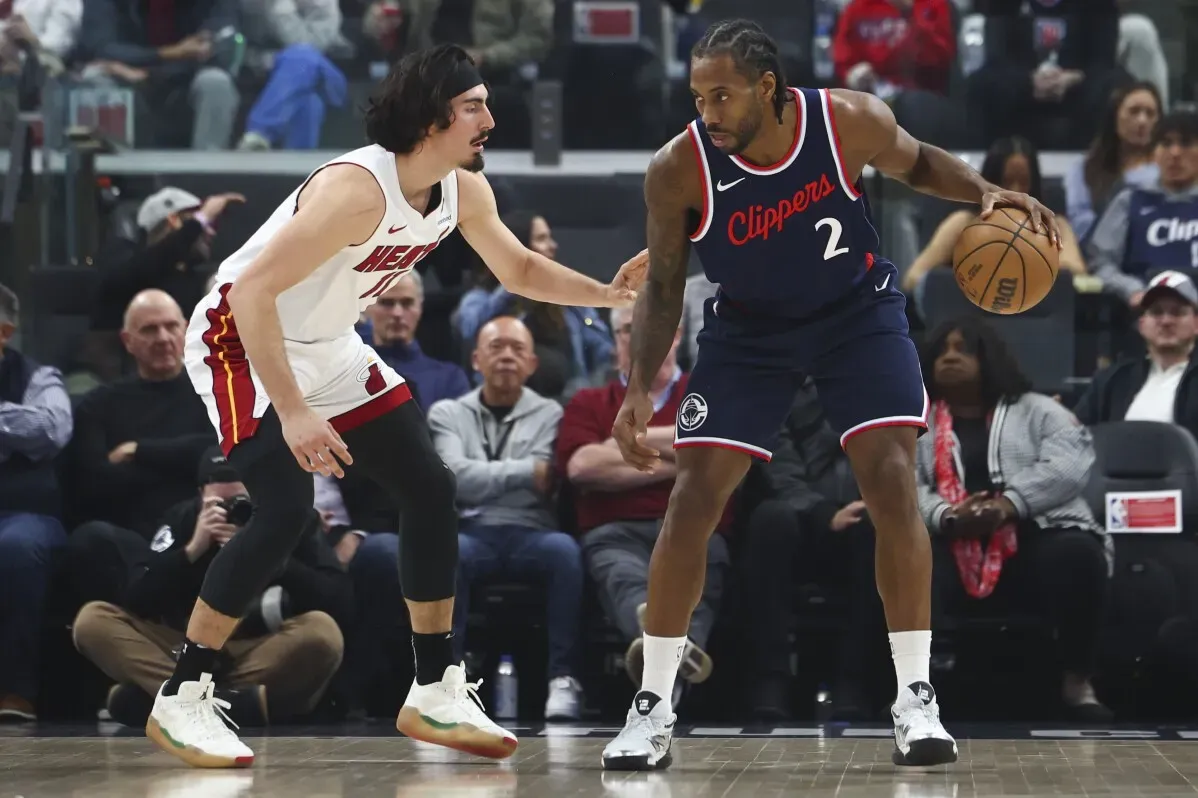 ليونارد يت dribble الكرة بينما يواجه لاعب ميامي هيت، مع جمهور في الخلفية. المباراة تظهر التنافس بين الفريقين.