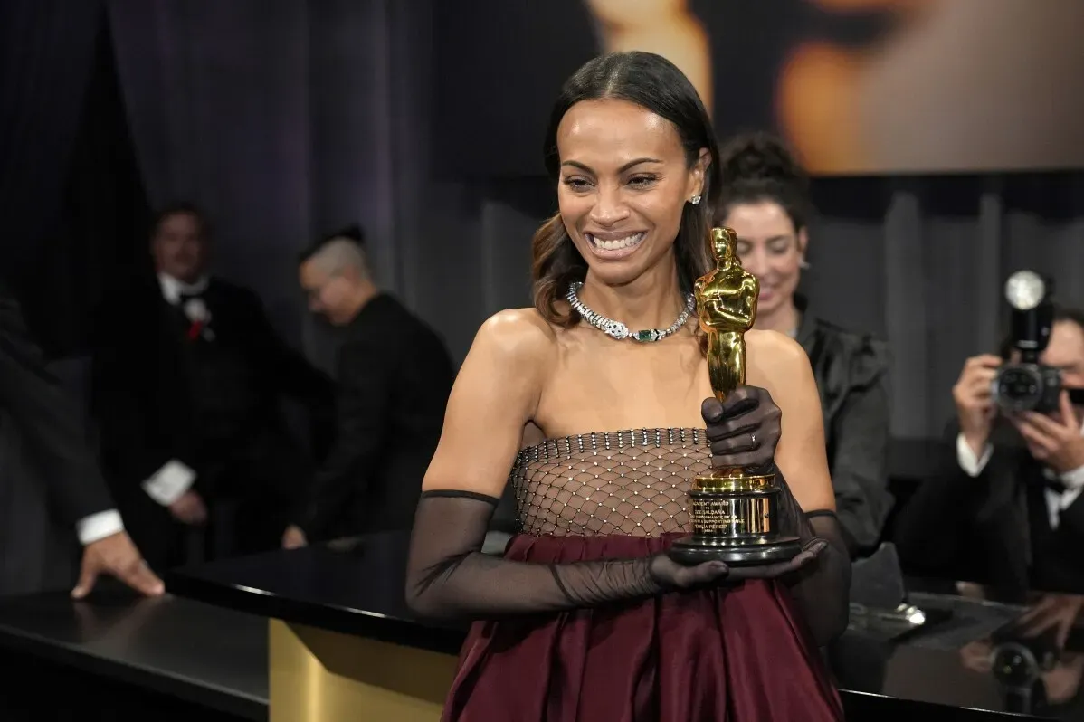 زوي سالدانيا تحمل جائزة الأوسكار لأفضل ممثلة مساعدة بفستان أنيق، تعبر عن مشاعرها تجاه عائلتها وتاريخها كابنة لمهاجرين.