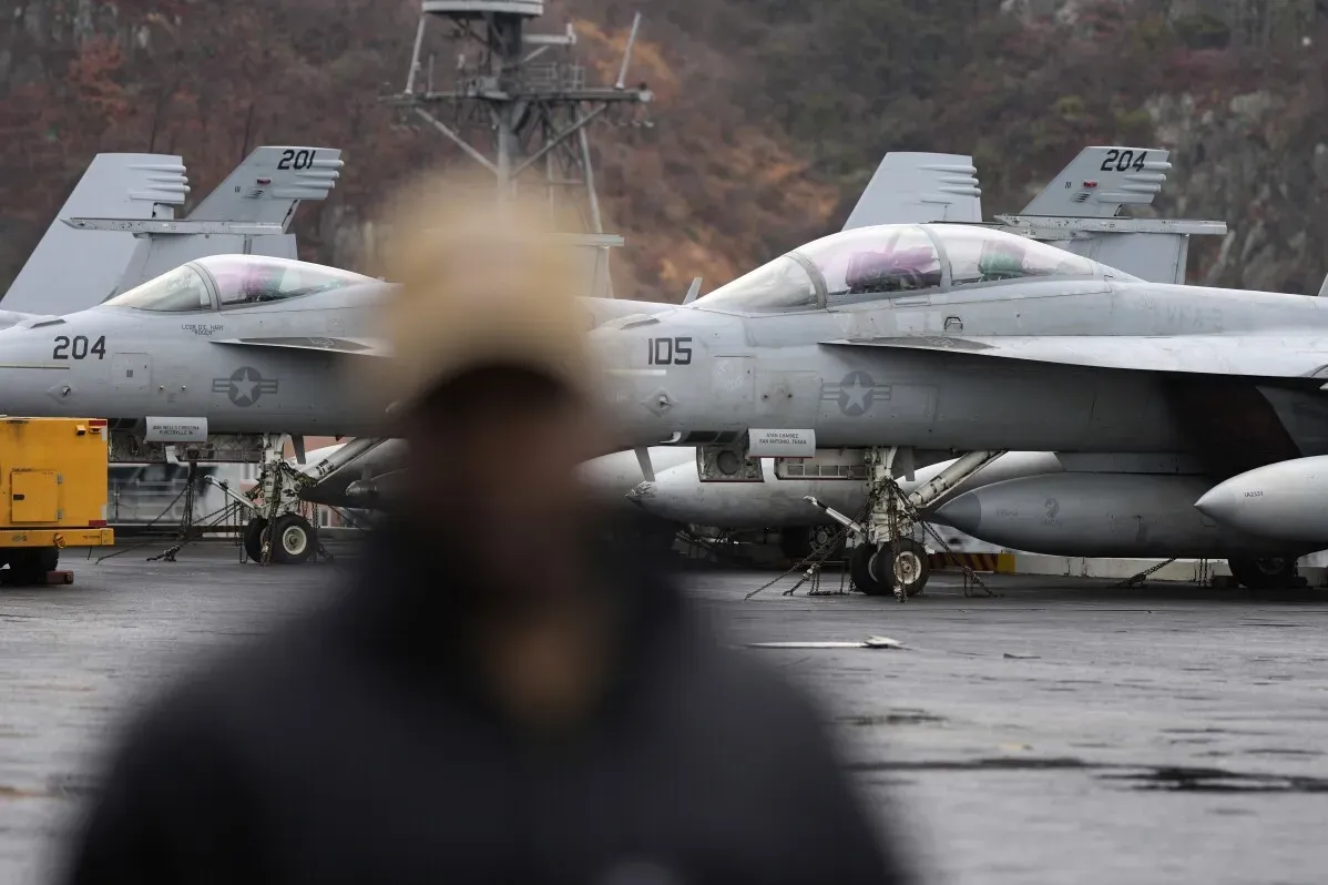تظهر الصورة طائرات حربية أمريكية من طراز F/A-18 في قاعدة عسكرية بكوريا الجنوبية، مع وجود شخص غير واضح في المقدمة.