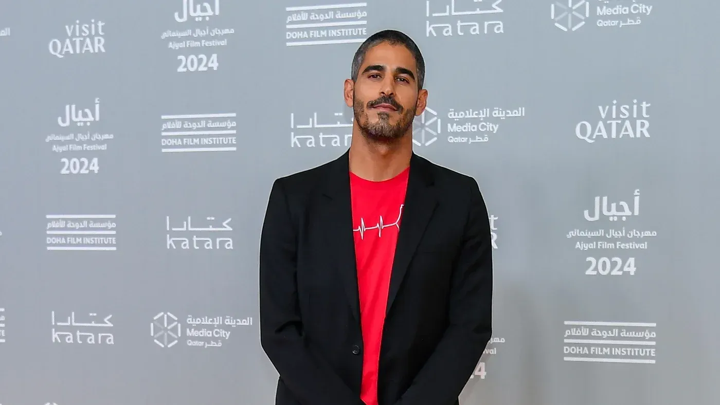 أحمد شهاب الدين، الصحفي الكويتي-الأمريكي، يظهر في مهرجان أجيال السينمائي 2024 بعد الإفراج عنه، مع خلفية تحمل شعارات المهرجان.