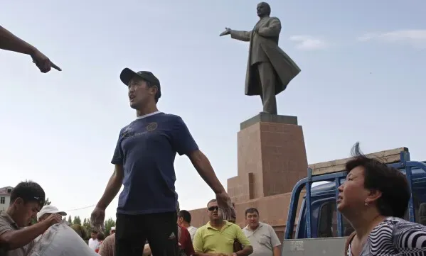إزالة تمثال فلاديمير لينين بطول 23 مترًا في أوش، قيرغيزستان، حيث يظهر شخصان يتحدثان في الخلفية.