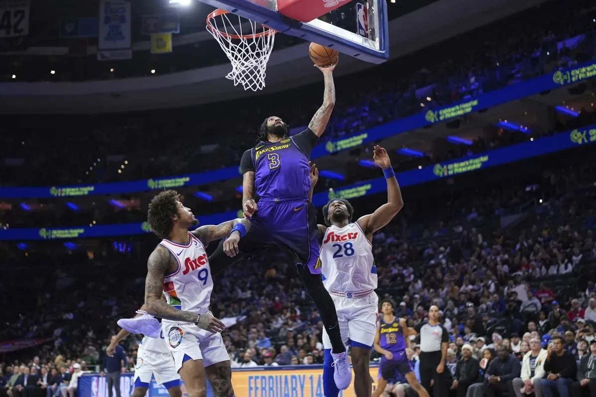 أنتوني ديفيس يسجل نقطة من فوق حارس فريق فيلادلفيا خلال مباراة في الدوري NBA، وسط تفاعل جماهيري حماسي.