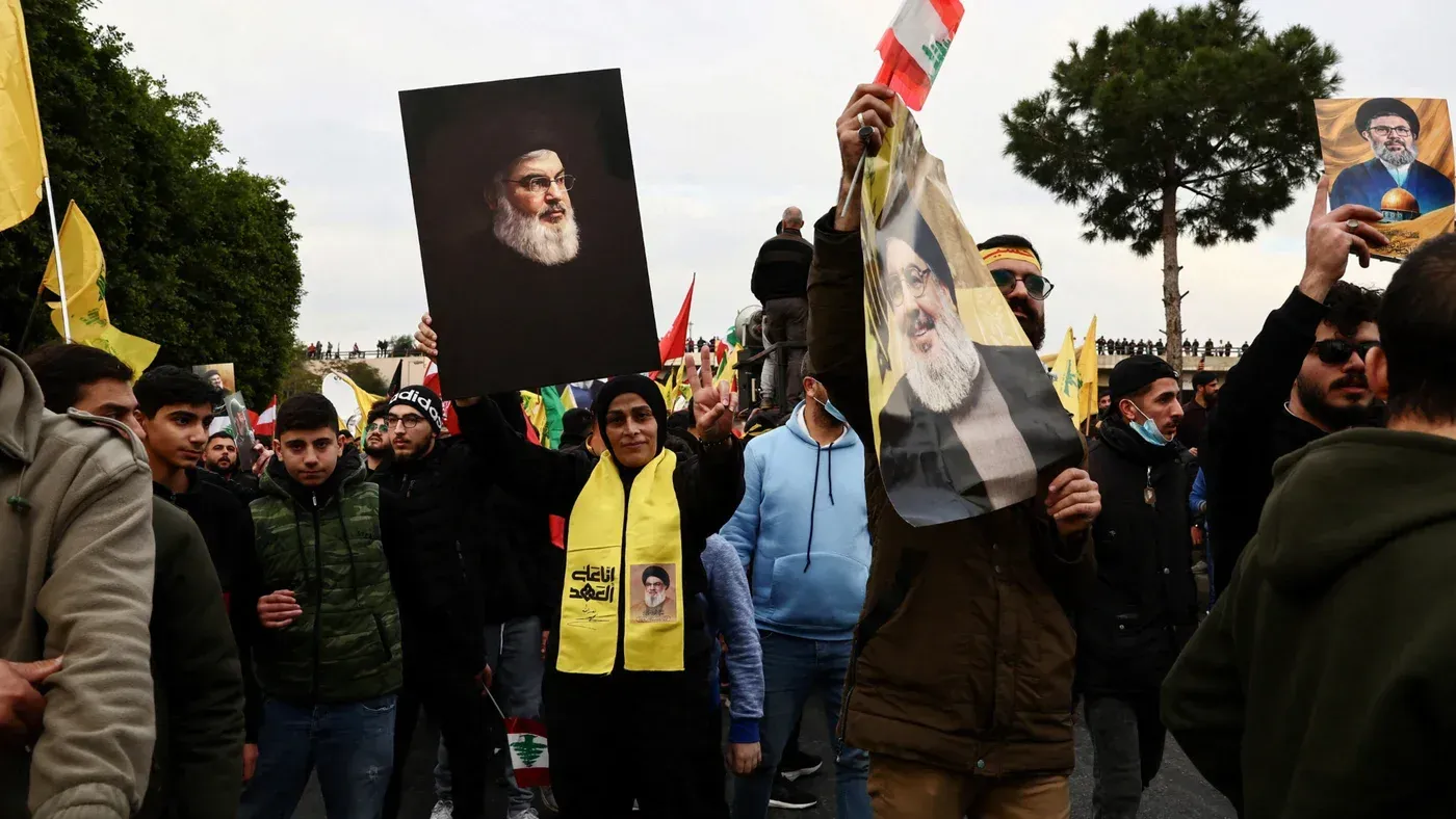 محتجون يحملون صورًا لحسن نصر الله ويهتفون خلال مظاهرة في لبنان، وسط أعلام حزب الله واحتجاجات ضد التدخلات الإسرائيلية.
