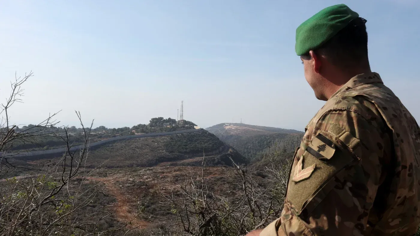 جندي لبناني يرتدي زيًا عسكريًا ويشاهد الحدود اللبنانية الإسرائيلية، في سياق التوترات البيئية والصحية الناتجة عن رش المواد الكيميائية.