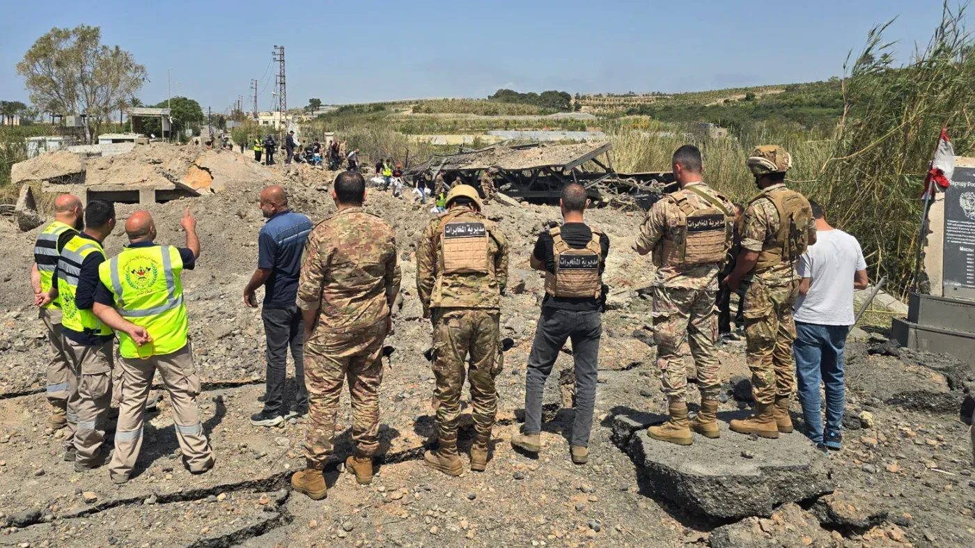 مجموعة من الأشخاص، بينهم جنود لبنانيون، يتفقدون موقعًا دمره انفجار في لبنان، وسط أجواء توتر بشأن وقف إطلاق النار.