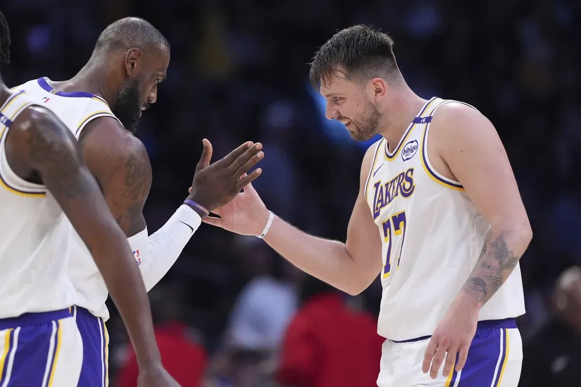 ليبرون جيمس ولاعب آخر من فريق ليكرز يتبادلان التحية بعد مباراة، مع التركيز على إنجاز جيمس في تسجيل 50,000 نقطة.