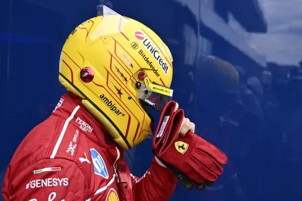 سائق فورمولا 1 يرتدي خوذة صفراء وقفازات حمراء، يستعد قبل السباق، مع التركيز على تحسين أداء فريقه في سباق جائزة المجر الكبرى.