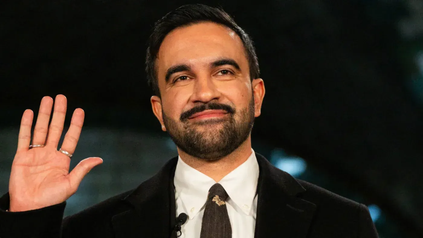 زهران ممداني، أول عمدة مسلم لنيويورك، يلوح بيده مبتسمًا خلال احتفالات رأس السنة الجديدة 2026 في قاعة المدينة.