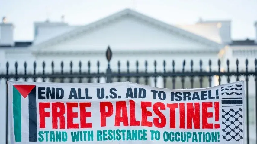 لافتة تطالب بإنهاء جميع المساعدات الأمريكية لإسرائيل، مكتوب عليها "حرروا فلسطين!"، تظهر أمام البيت الأبيض.