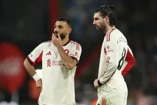 لاعبو ليفربول يتحدثون معًا خلال مباراة، مع التركيز على تعبيراتهم الجادة بعد الهزيمة. تعكس الصورة التحديات التي يواجهها الفريق في الدوري الإنجليزي.