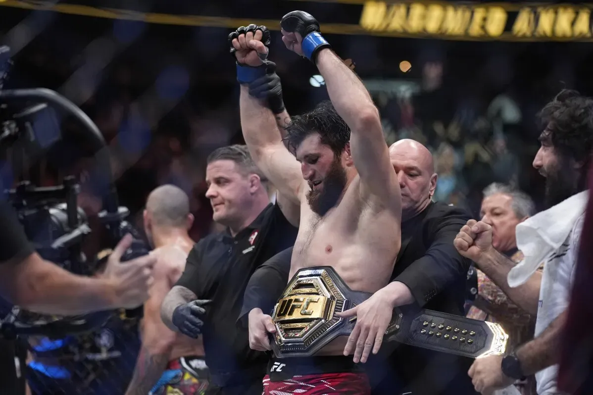 ماغوميد أنكالاييف يحتفل بفوزه بحزام الوزن الثقيل الخفيف في UFC 313 بعد قرار بالإجماع، وسط أجواء حماسية في الحلبة.
