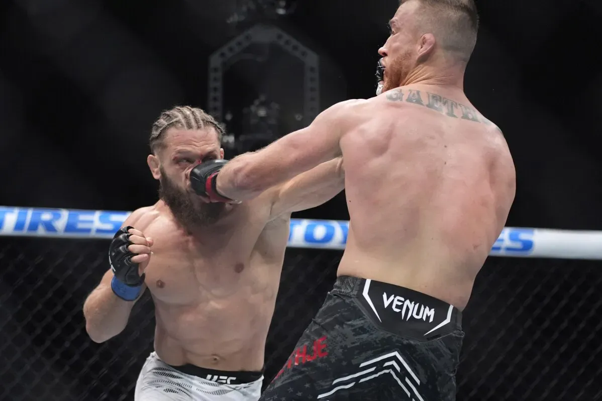 مقاتل في قفص UFC يتلقى ضربة قوية من خصمه، مع التركيز على الحركات الديناميكية والتوتر في النزال.