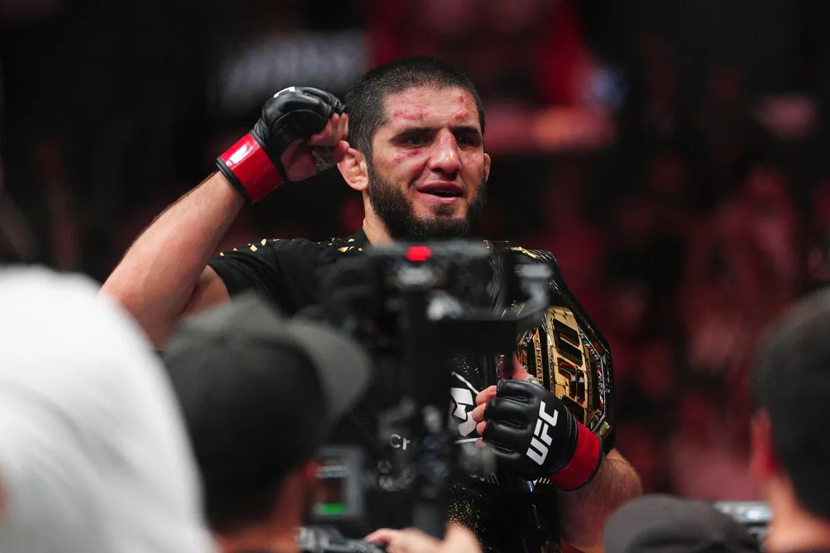 إسلام ماخاشيف يحمل حزام بطولة UFC ويظهر وجهه مصابًا بجروح وكدمات بعد فوزه في مباراة UFC 330.