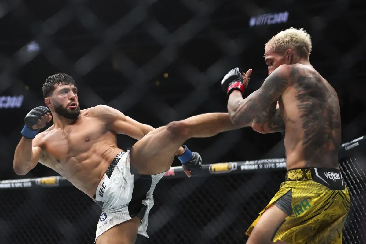 ماخاتشيف ينفذ ركلة قوية أثناء نزال UFC، مستعرضًا مهاراته في الفنون القتالية ضد خصمه تساروكيان في حلبة القتال.