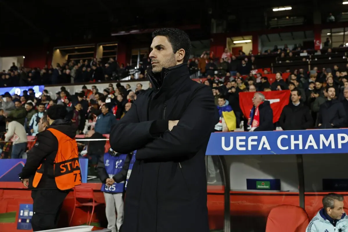 ميكل أرتيتا، مدرب أرسنال، يقف في الملعب أمام جمهور متحمس، مع لافتة دوري أبطال أوروبا خلفه، خلال مباراة حاسمة في الموسم.