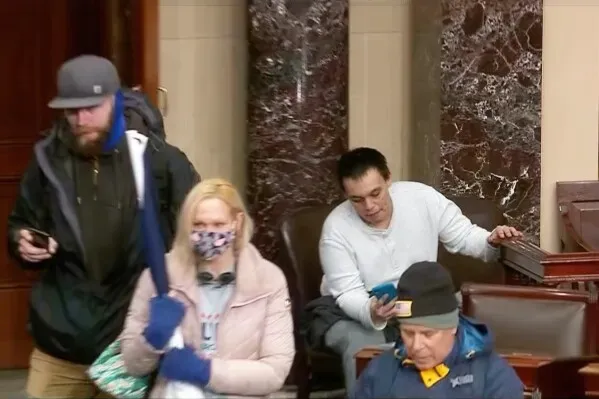 مجموعة من الأشخاص داخل مبنى الكابيتول الأمريكي، بعضهم يحمل هواتفهم، يظهرون في لحظة من الفوضى خلال أحداث 6 يناير.