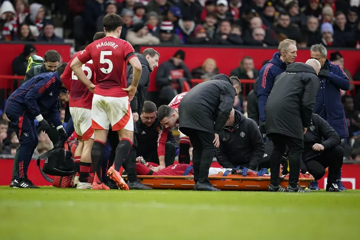 لاعب مانشستر يونايتد ليساندرو مارتينيز يتلقى العلاج بعد إصابته في الركبة اليسرى، محمولاً على نقالة وسط قلق زملائه والجماهير.