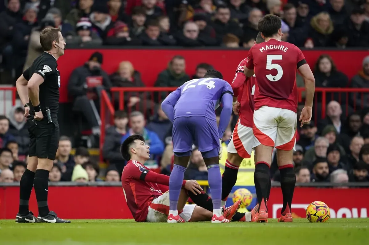 لاعب مانشستر يونايتد ليساندرو مارتينيز مصاب على الأرض، محاط بزملائه وحكم المباراة، بعد إصابته في الركبة خلال مباراة ضد كريستال بالاس.
