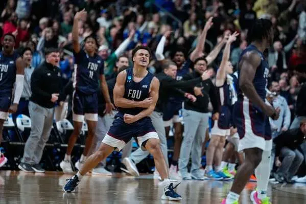 احتفال لاعب فريق FDU بعد تسجيل نقطة حاسمة في مباراة NCAA، مع تفاعل حماسي من زملائه في الفريق والجمهور.