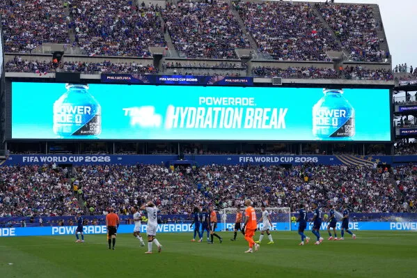 استراحة ترطيب خلال مباراة في كأس العالم 2026، مع عرض إعلانات على الشاشة الكبيرة، وجمهور كبير في الملعب.