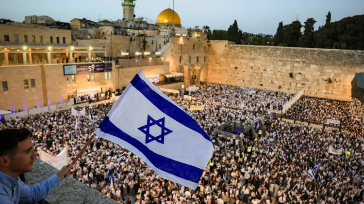حشد كبير من المحتفلين في حائط البراق بالقدس، يحملون الأعلام الإسرائيلية، مع ظهور قبة الصخرة في الخلفية، خلال مسيرة الأعلام.