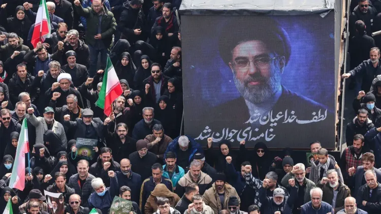 تجمع حشود من الناس في مظاهرة تأييد للقيادة الإيرانية، مع صورة للمرشد الأعلى الجديد مجتبى خامنئي في الخلفية.