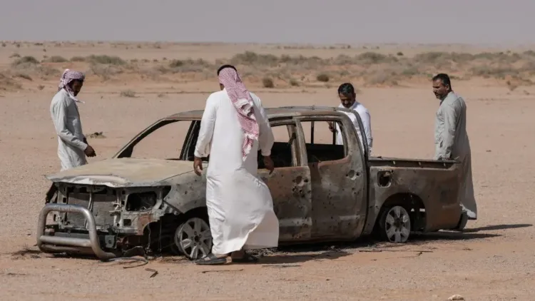 رجال يتفقدون شاحنة محترقة في الصحراء العراقية، حيث عُثر عليها بعد مقتل الراعي عوض الشمري بالقرب من قاعدة إسرائيلية سرية.