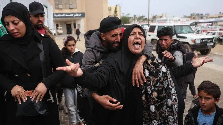 مشهد عاطفي لعائلات فلسطينية في خان يونس، تعبر عن الحزن بعد الهجمات الإسرائيلية، مع وجود أطفال ونساء ورجال في الخلفية.