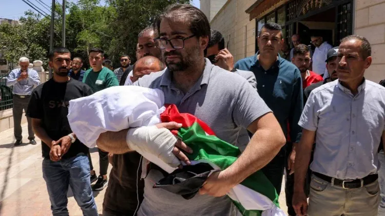 والد يحمل جثمان طفله سام فهد أبو هيكل، الذي قُتل برصاص جنود إسرائيليين، وسط حشود من المعزين في الخليل.