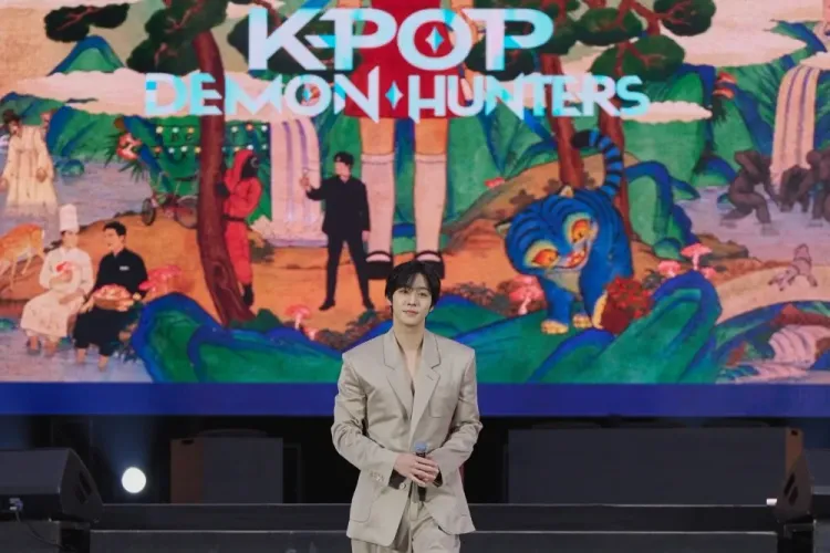 ممثل كوري يقف على المسرح في مهرجان Netflix Janchi بسيول مع خلفية عرض شعار مسلسل KPop Demon Hunters، احتفالاً بالمحتوى الكوري.