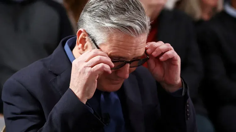 كير ستارمر، زعيم حزب العمال البريطاني، يضع نظارته أثناء حديثه في حدث عام، مع تعبير جاد يعكس التحديات السياسية الراهنة.