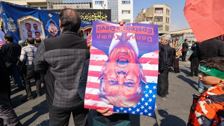 محتجون إيرانيون يحملون لافتة مقلوبة تحمل صورة للرئيس الأمريكي السابق دونالد ترامب، تعبيرًا عن رفضهم للسياسات الأمريكية.